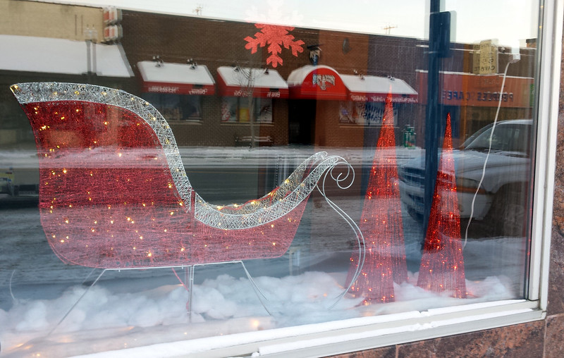 red wire sleigh and three red wire conical trees in a window