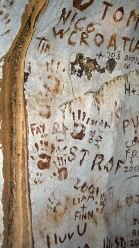 Handprints and names painted with red mud on the walls of a cave in Vang Vieng, Laos