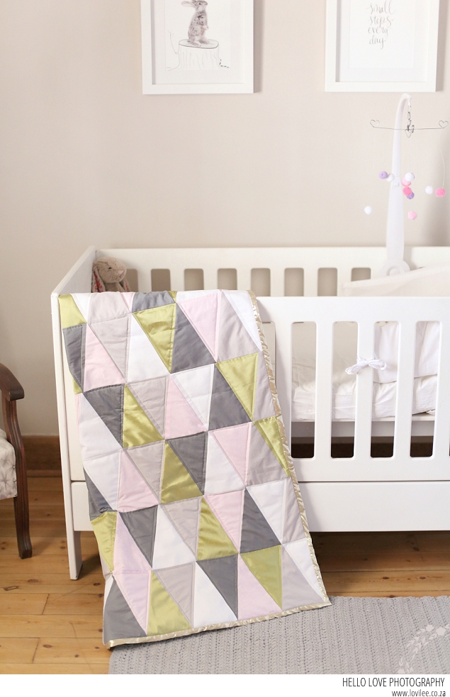 A soft tone girl's nursery with geometric quilt