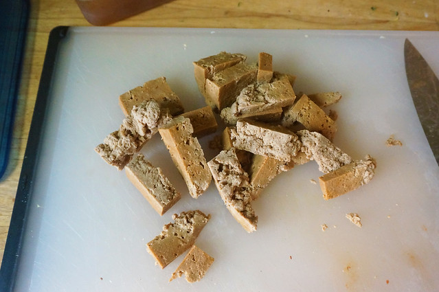 A pile of seitan, chopped into bitesize pieces (ok, honestly, chopped WAY too big since this is a photo from an early test run), resting on a white cutting board.