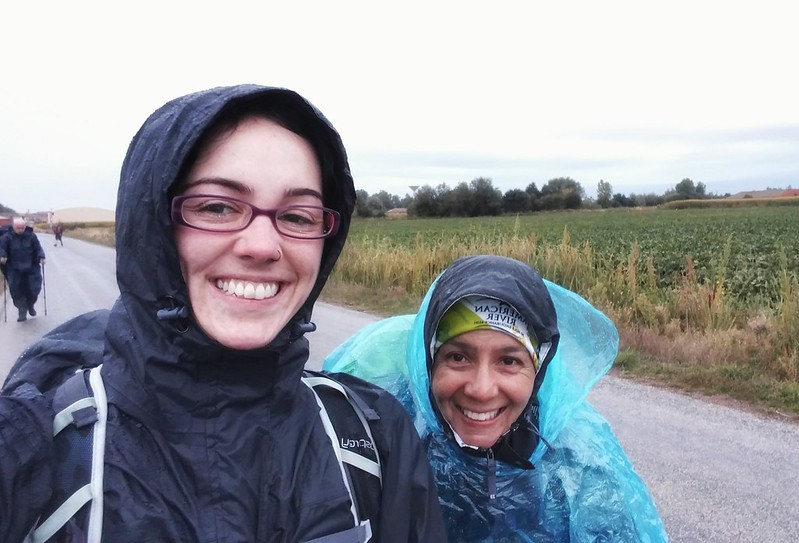 Two female pilgrims smiling in waterproofs on the Camino 